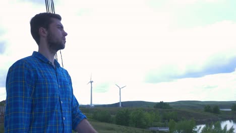 man standing by wind turbines by a lake