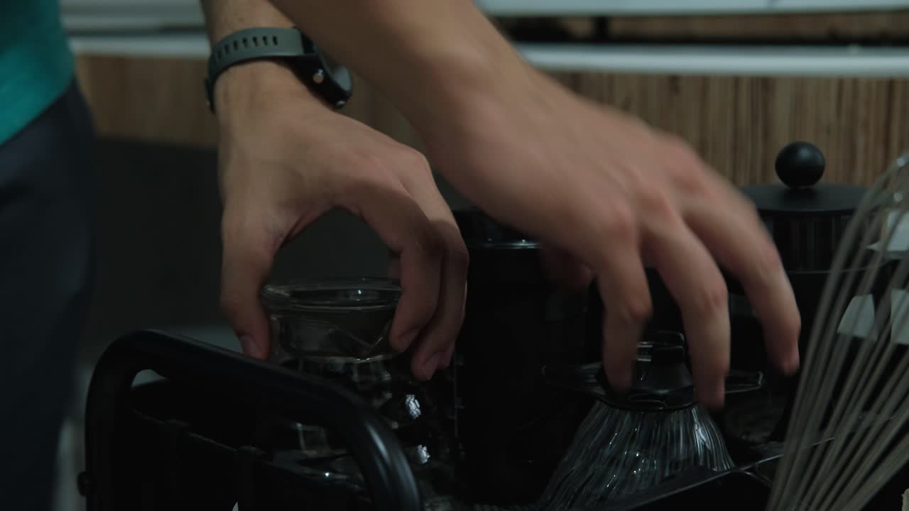 Static shot of coffee-making accessories being placed on a cart in kitchen.