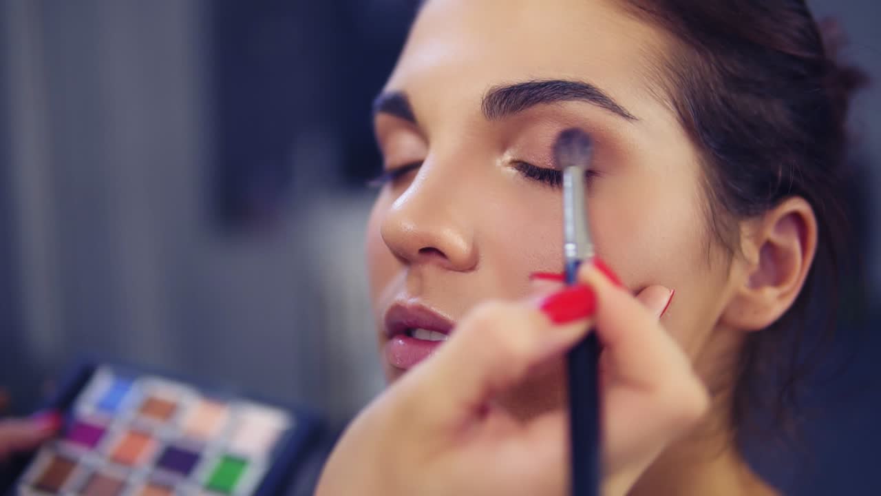 artista de maquillaje profesional aplicando sombra de ojos al ojo del modelo utilizando un pincel especial. belleza, maquillaje y concepto de moda. cámara lenta