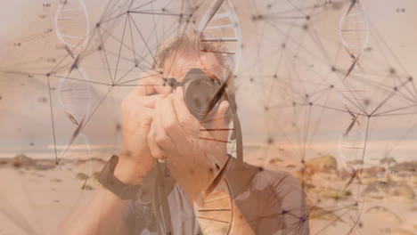 Male photographer capturing rocky beach, overlaying DNA helix and network nodes for tech industry