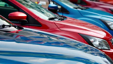 a row of red and blue cars parked in a parking lot