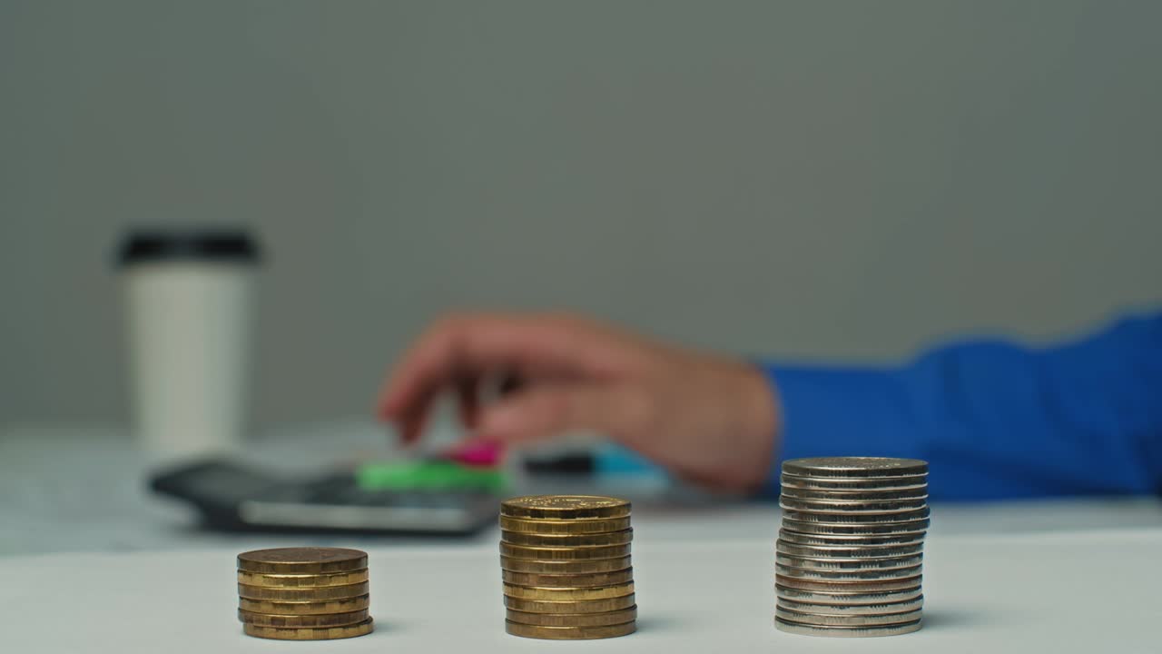 cerca de las manos de un hombre calcula los gastos, comprobando la información de las tablas, calculadora, diagramas en la mesa.