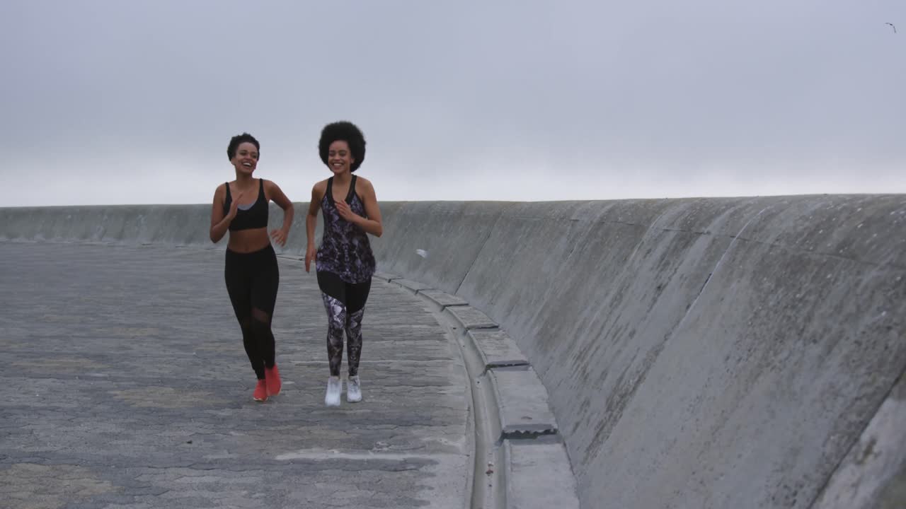 dos mujeres de raza mixta corriendo en los muelles
