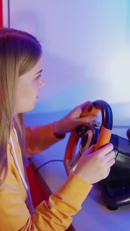 girl playing on computer with steering wheel. young woman enjoying car racing video game at home