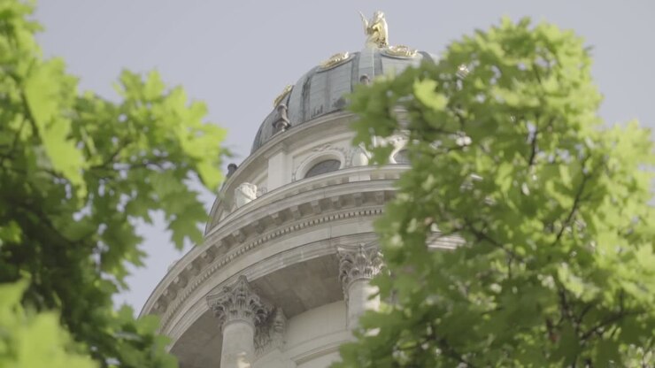 SLOW MOTION Cattedrale Francese del Gendarmenmarkt a Berlino tra due alberi verdi.