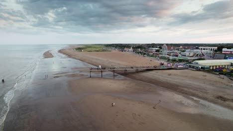a medida que se pone el sol, el muelle de skegness toma el centro del escenario en este video aéreo, con personas disfrutando de un paseo tranquilo a lo largo del muelle de madera