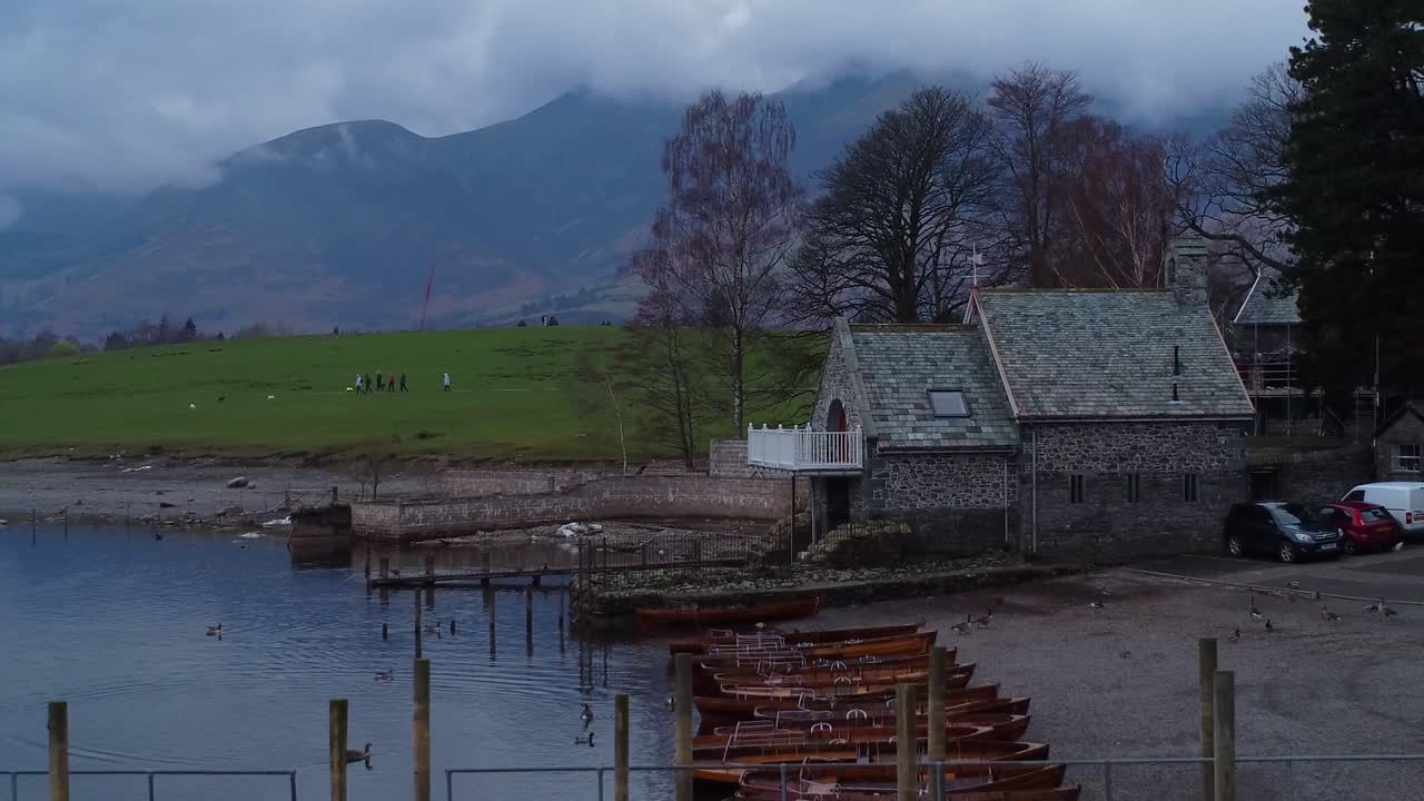 vídeo cinematográfico de drones aéreos en 4k, moviéndose lentamente hacia atrás en derwent water, keswick con skiddaw y nubes en el fondo