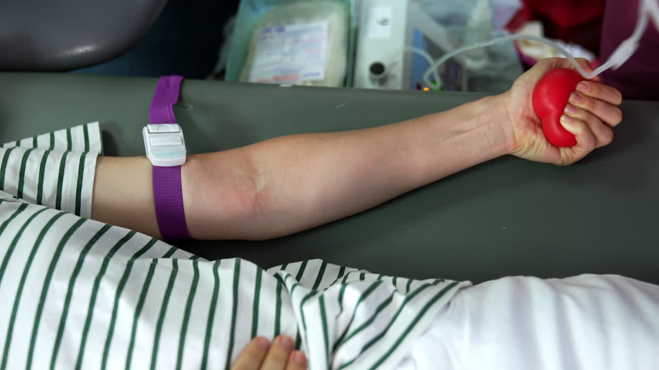 Medic covers the donor's hand with antiseptic before inserting the needle. Nurse attaches the drip to the arm.