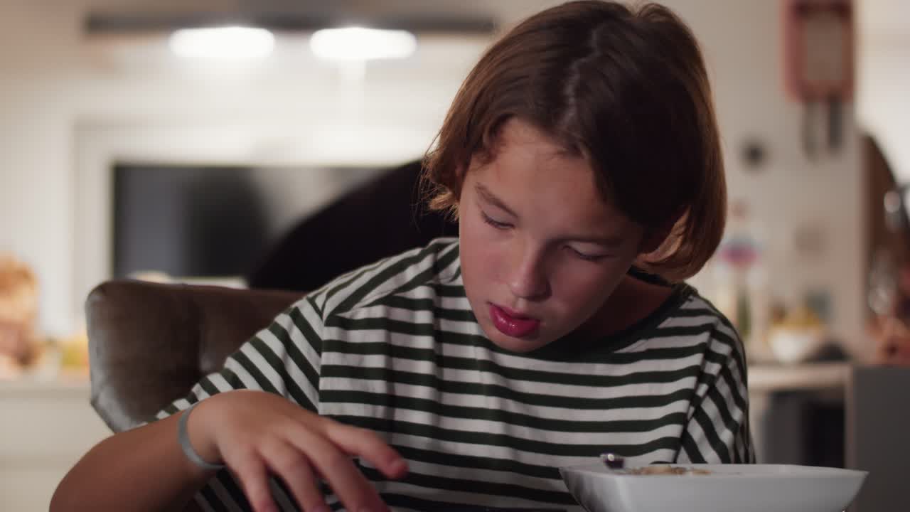 Ragazzo che mangia pasta e guarda video in cucina