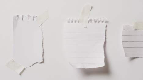 video de un primer plano de tres trozos de papel con espacio de copia pegado en un fondo blanco
