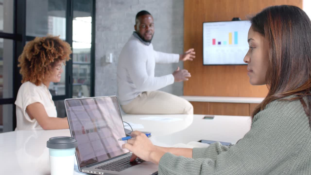 Diverse male and female colleagues using laptop and monitor at office meeting, slow motion