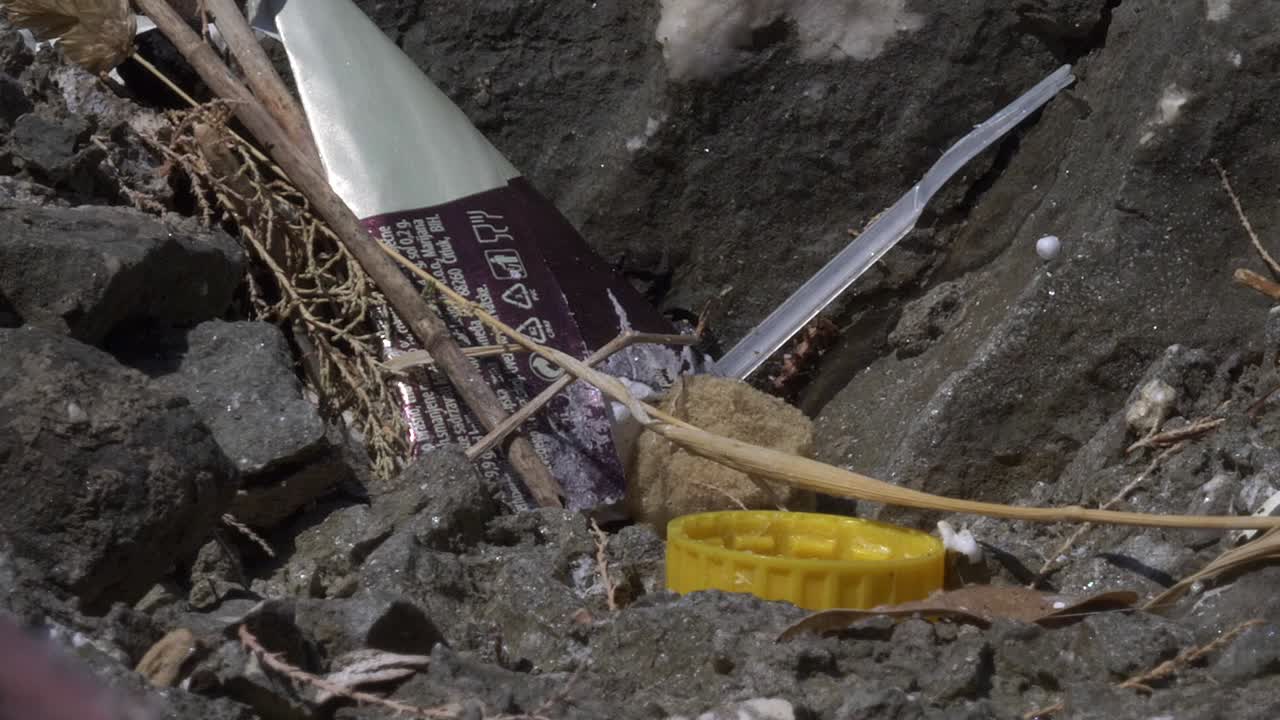 Yellow bottle cap and other plastic litter in the ground. Plastic waste pollution. Ecology concept.