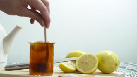 making a cup of tea with sugar and lemon wedges. on wooden cutting board.
