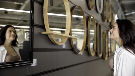 a lady visits a store and chooses a mirror. woman shopping for home.