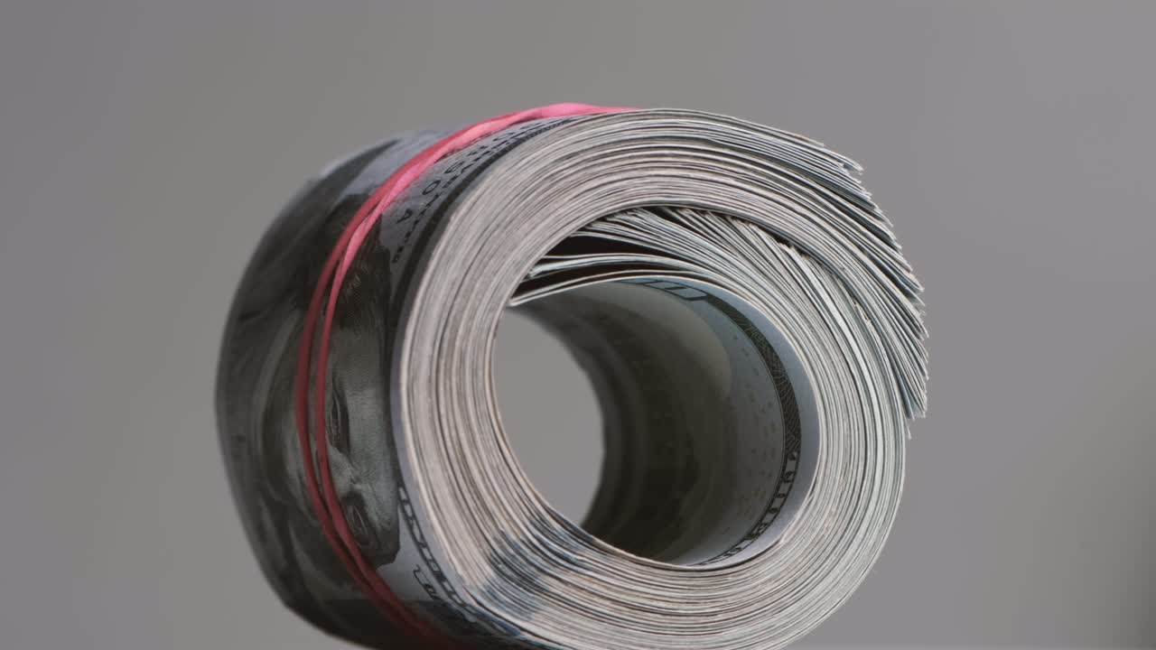 100달러 지폐의 클로즈업 롤은 탄력적인 밴드로 어져 있습니다.