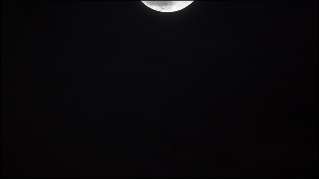 Waning moon crossing the sky between clouds