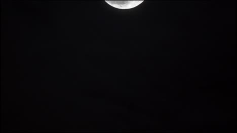 waning moon crossing the sky between clouds
