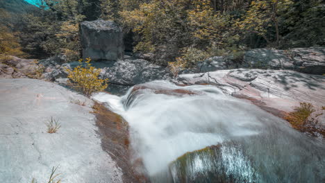 Cascading-waterfall-in-a-serene-forest,-smooth-water-flow-over-rocks,-daylight,-timelapse