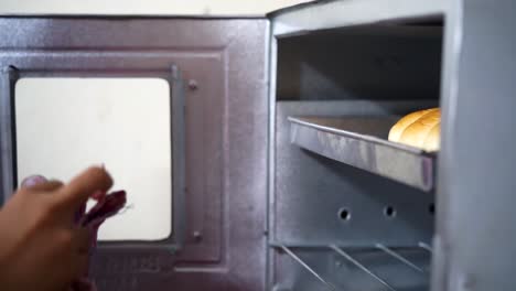 Asian-woman-taking-out-baked-Bread-from-the-oven-before-Holiday