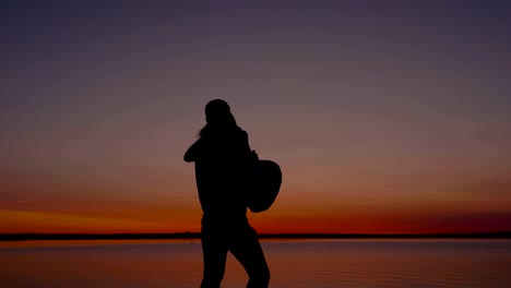 silhouette of a man holding a woman and circling her at sunset by the sea