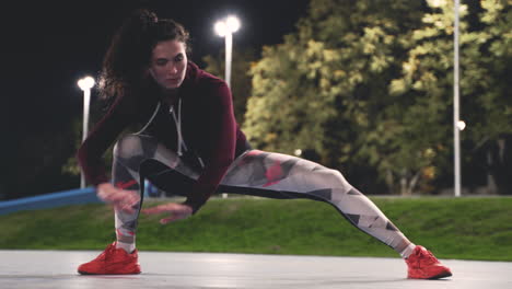 sportive curly girl training and stretching legs in the park at night 1