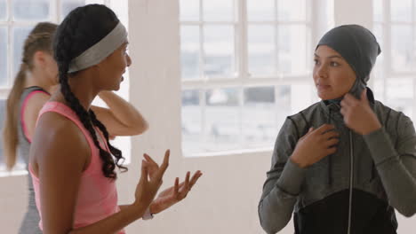 beautiful young muslim woman chatting to friend in yoga class discussing healthy fitness lifestyle enjoying conversation in studio wearing headscarf