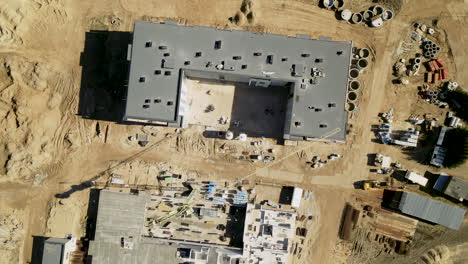 aerial drone spinning around the construction site of two multistoried new modern buildings in lubawa, poland