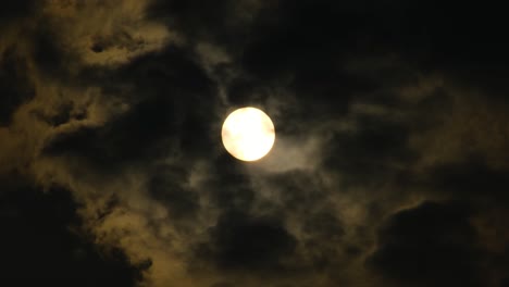 Gelber-Mond-Oder-Gelbe-Sonne,-Gesehen-Durch-Flecken-Dunkler-Wolken,-Die-Sich-Im-Wind-Bewegen