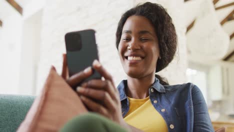 Vídeo-De-Una-Mujer-Afroamericana-Feliz-En-Un-Sofá-Usando-Un-Teléfono-Inteligente
