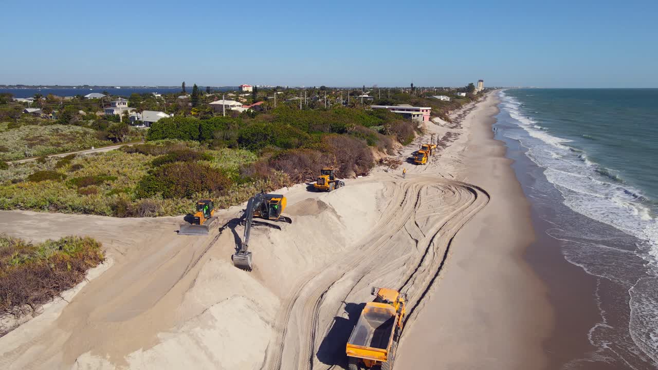 tomada de drones de 4k de excavadoras que conducen en la playa cerca del agua del océano