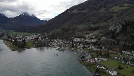 Community-on-lake-shoreline-with-boats-and-hotels-overlooking-water-in-Walensee-Switzerland