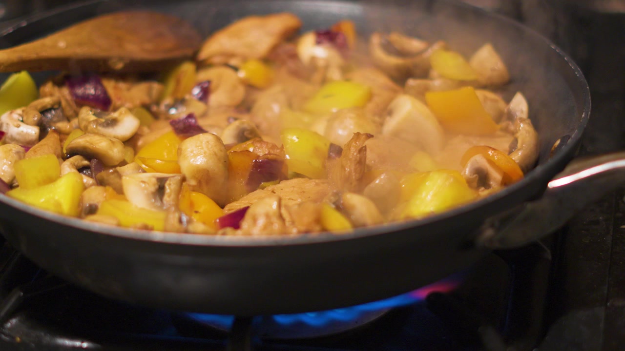 Cooking Footage of Various Vegetables and Chicken Simmering in Hot Pan with Gas Fired Stove Underneath 4K