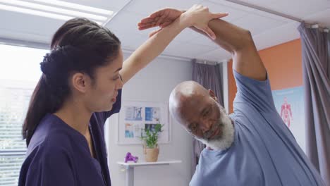 Diverse-senior-male-patient-and-female-physiotherapist-working-during-physical-therapy-session