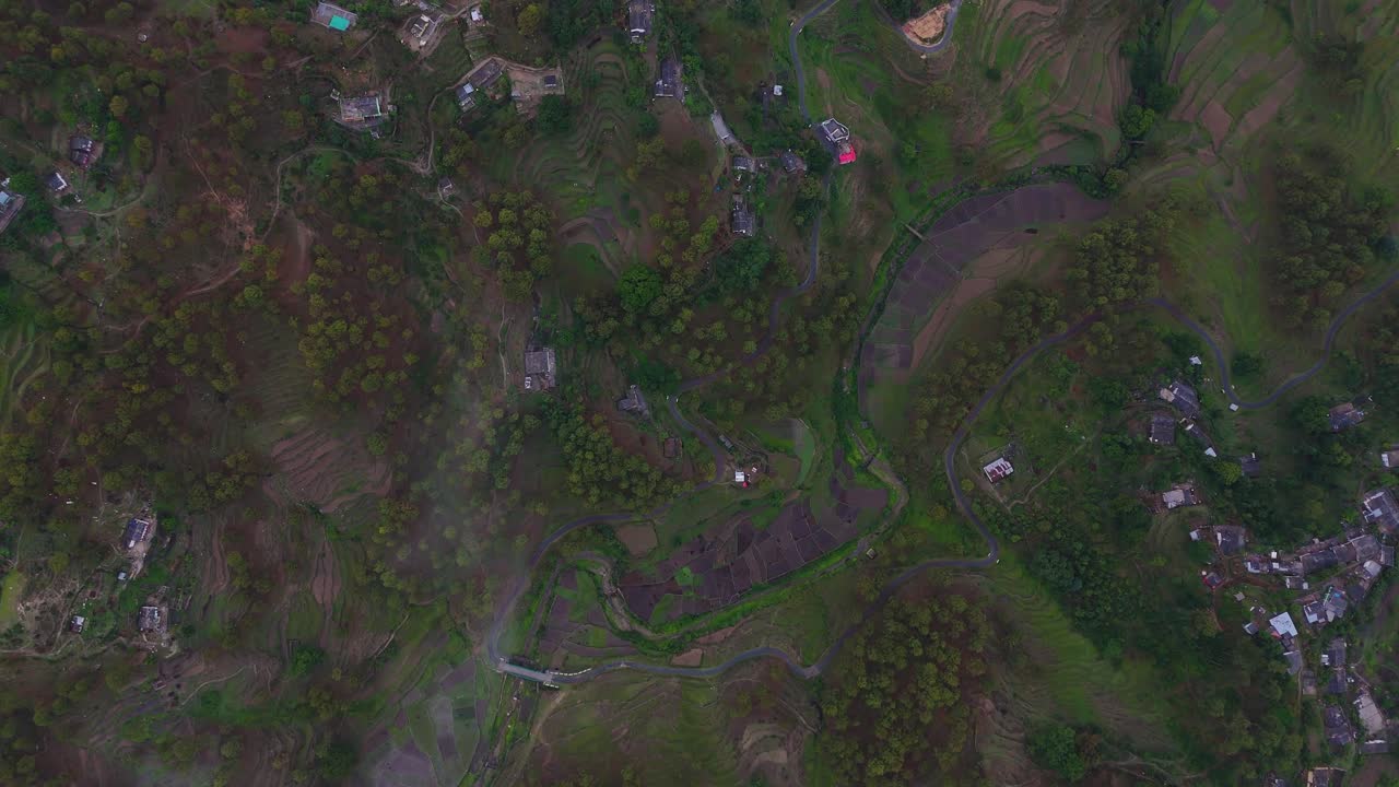 Aerial drone shot capturing a small village nestled in the heart of towering mountain ranges.