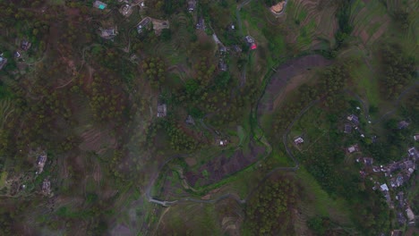 aerial drone shot capturing a small village nestled in the heart of towering mountain ranges.