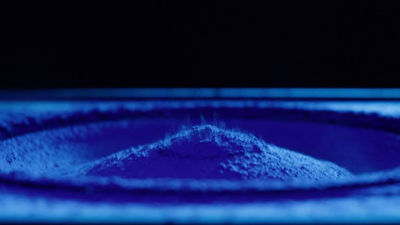 Polvere blu che vibra e danza sul cono di un altoparlante.