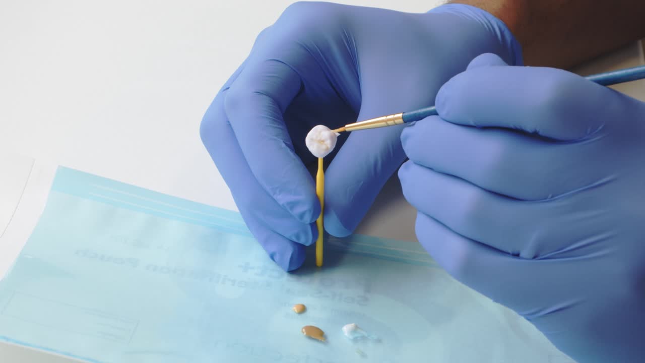 Dentist painting and prepping a custom crown replacement for patient's tooth