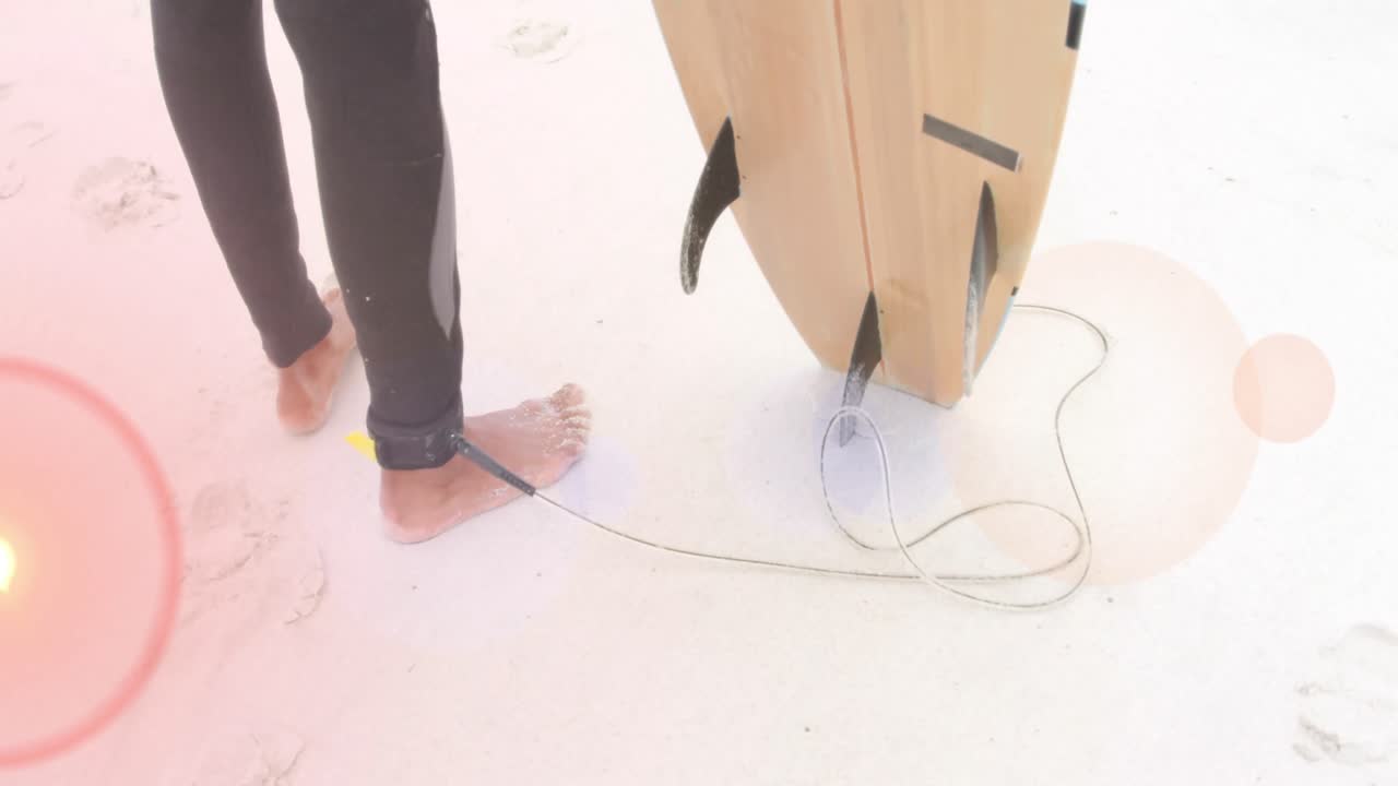 서핑 보드를 들고 있는 해변에 있는 서핑 선수의 발 위에 있는 색 ⁇ 의 빛 반점들의 애니메이션