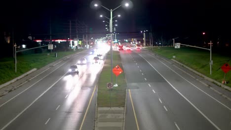 vehicles drive under a bridge that the view is from on a highway in the late evening