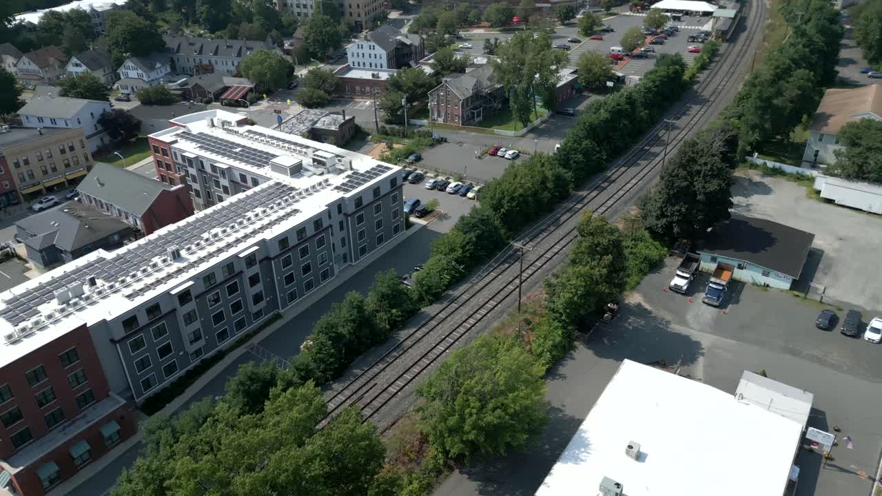 el dolly aéreo se inclina por encima de las vías del tren y el edificio de apartamentos con paneles solares, northampton massachusetts