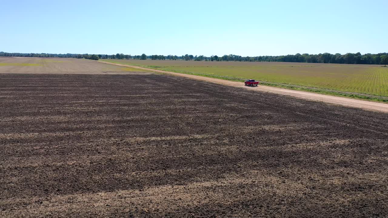 toma aérea de una camioneta roja que viaja por un camino de tierra en una zona agrícola rural de mississippi 5