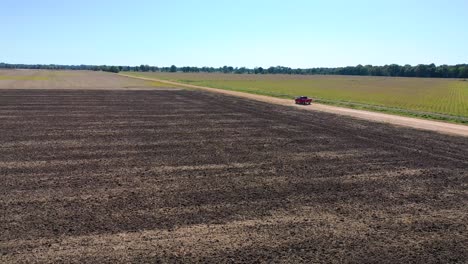 Aerial-shot-of-a-red-pickup-truck-traveling-on-a-dirt-road-in-a-rural-farm-area-of-Mississippi-5