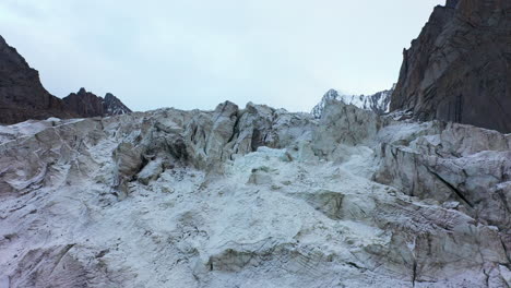 reveladora toma de drones de un colgante rocoso cubierto de nieve para revelar el glaciar ak-sai en kirguistán