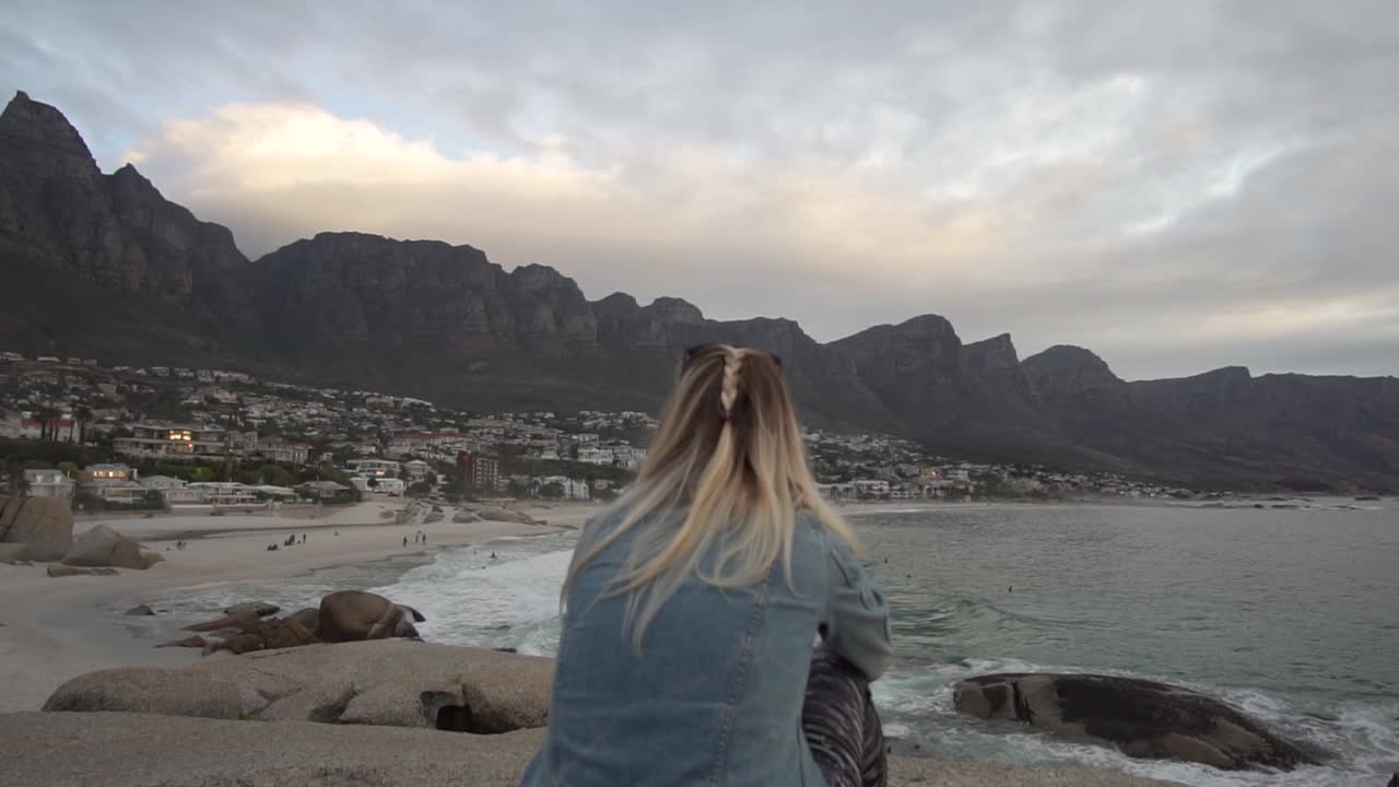 Girl looking at the Coastline of Camps Bay in Cape Town with Table Mountain in the background in Slow Motion
