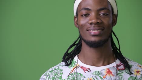 joven hombre africano guapo con dreadlocks contra un fondo verde