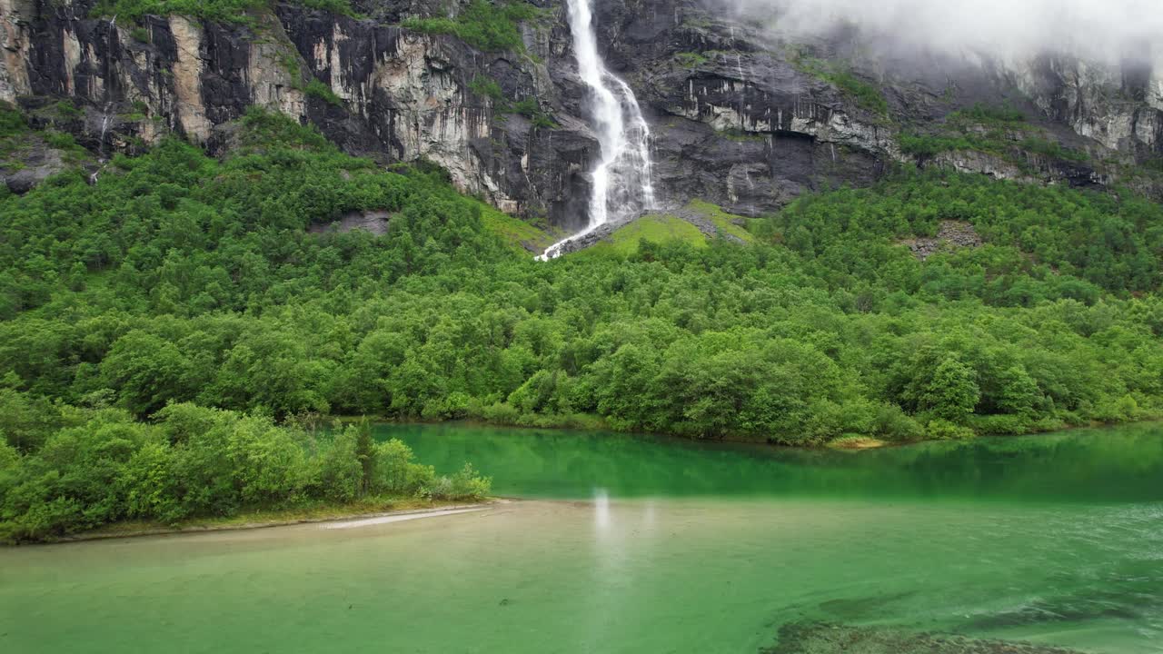 Waterfall and green lake in the mountains of Norway