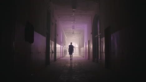 a bald man walks on the empty hospital corridor at night