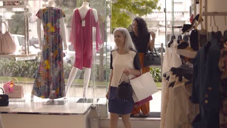 two happy female friends coming in fashion store together