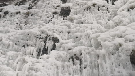 rocky cliff covered with ice and icicles at wintertime