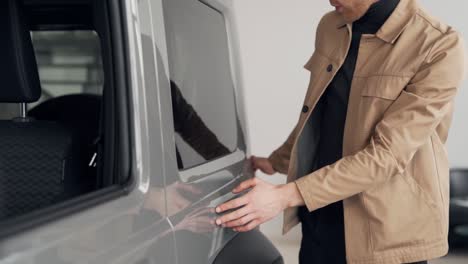 joven feliz satisfecho con la calidad de la pintura del coche